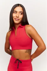 Top deportivo color rojo vibrante, sin mangas, con cuello polo y escote en V. Presenta un corte crop ajustado al cuerpo.