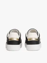 Zapatillas de corte bajo estilo tenis, confeccionadas en piel color negro. Presentan suela de goma blanca, detalle metalizado en el talón, ojal superior dorado y monograma TH metálico en el lateral.