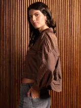 Campera corta de tela fina con diseño de paneles combinados, cuello camisero, cierre frontal con botones dorados y costuras a contratono.