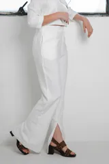 Conjunto de dos piezas color blanco compuesto por un blazer corto de manga 3/4 con cuello solapa y un pantalón de corte wide leg con tajo lateral en el dobladillo.