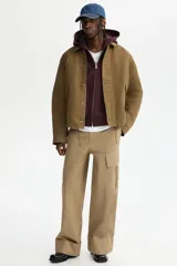 Campera de sarga levemente acolchada con cuello inglés, cierre frontal y solapa con botones. Presenta mangas raglán, bolsillos insertados delanteros y cordón ajustable en el bajo.