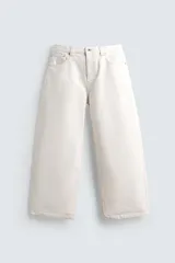 Pantalón de jeans de algodón, color blanco roto o crudo, con corte balloon fit (relajado desde la cadera y ligeramente estrechado en el bajo) y tiro medio. Presenta cinco bolsillos y efecto lavado.