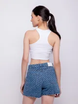 Short de jean azul con textura de roturas, tiro alto, cinco bolsillos, botón y cierre metálico.