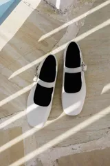Zapato plano estilo Mary Jane de cuero negro, con punta fina y tira ajustable con hebilla sobre el empeine.