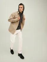 Pantalón de jean color beige, corte recto, con cinco bolsillos y cierre de cremallera.