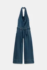 Mono de denim de pierna ancha con cuello halter fluido y espalda descubierta. Incluye cinturón del mismo tejido para ajustar en la cintura, bolsillos delanteros y cierre lateral con cremallera.