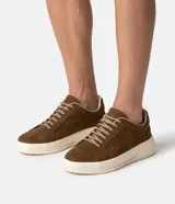 Championes masculinos de cuero nobuk marrón, con diseño minimalista, cordones elásticos y suela tipo caja de perfil elevado en color marfil.