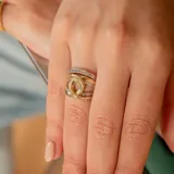 Anillo de oro 10k con diseño de nudo central y bandas laterales decoradas con circonias brillantes.