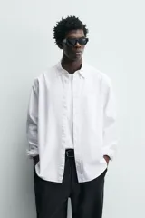 Camisa de corte regular fit confeccionada en tejido de algodón con diseño de rayas verticales. Presenta cuello abotonado, manga larga con puños abotonados, bolsillo plastrón en el pecho y cierre frontal con botones.