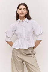Camisa azul marino de cuello clásico, mangas abullonadas a tres cuartos y detalle fruncido en el frente. Presenta una silueta amplia y diseño corto con vuelo en el ruedo.
