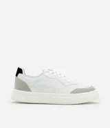 Championes urbanos blancos de material sintético con detalles en gris y negro. Presentan punta redonda, cordones, perforaciones para mayor respirabilidad y suela bold.