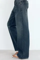 Jeans de tiro medio con corte relajado y diseño de cinco bolsillos. Presenta trabillas en la cintura, cierre frontal con cremallera y botón metálico, con un acabado de lavado desgastado.