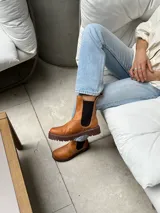 Bota de cuero color marrón con elásticos laterales negros, caña baja y suela negra artesanal de neolite.