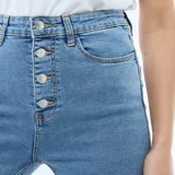 Pantalón jean de corte super skinny, tiro alto con cierre frontal de botones expuestos, confeccionado en denim elástico de color azul medio.