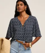Blusa tipo bata de color azul marino con estampa de follaje en tonos claros. Presenta escote en V con detalle de abalorio y mangas cortas amplias.
