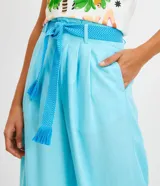 Pantalón acampanado de lino color celeste, con bolsillos, cinturón bordado y pliegues delanteros.