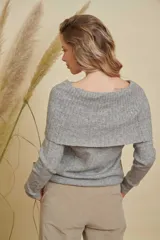 Buzo de tejido de punto color gris, con diseño de cuello amplio que permite usarlo con los hombros descubiertos o como cuello tipo buche. Presenta mangas largas y un calce holgado.