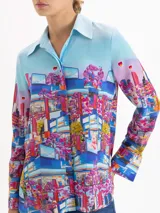 Camisa de seda con cuello clásico, manga larga y cierre frontal con botones ocultos. Presenta un estampado artístico colorido con motivos urbanos y naturales de la cápsula Il Bunny Porta Fortuna.