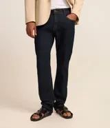 Pantalón slim de jean azul oscuro para hombre, con diseño de cinco bolsillos, presillas para cinturón y cierre frontal con botón y cremallera.