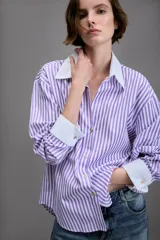 Camisa de manga larga con cuello solapa y puños en contraste color blanco. Presenta un diseño de rayas verticales en color lila y blanco, con cierre frontal de botones.
