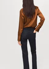 Camisa de corte recto con acabado satinado, cuello camisero clásico, cierre frontal con botones y mangas largas con puños abotonados.