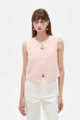 Musculosa cropped de viscosa color rosado, con cuello a la base, pequeña abertura frontal y detalle de hebilla metálica decorativa.
