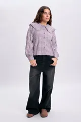 Camisa de manga larga con estampa a cuadros en tonos violeta y blanco, con cuello babero amplio con volados y cierre frontal abotonado.