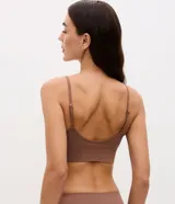 Soutien tipo top de color negro, confeccionado en tejido seamless texturizado con tirantes finos ajustables. Cuenta con copas desmontables y diseño sin costuras.