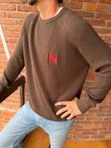 Sweater de tejido de punto acanalado en color marrón, con cuello redondo, mangas largas y bordado distintivo en color rojo en el pecho.