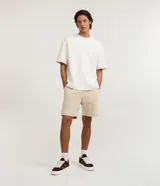 Bermuda masculina de corte slim, confeccionada en tejido de algodón con felpa. Presenta cintura elástica con cordón ajustable, bolsillos laterales y una pequeña etiqueta aplicada en el ruedo.