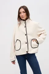 Campera de sherpa doble faz color bordó, con cierre frontal de botones, cuello alto y bolsillos laterales. Presenta detalles de vivos en nylon color tostado en los bordes y costuras.