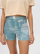 Short tipo biker de tiro alto, confeccionado en lycra con un diseño estampado estilo tie-dye en tonos azul y blanco.