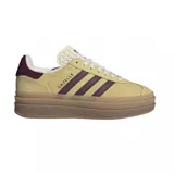 Championes adidas modelo Gazelle Bold, con diseño de plataforma de triple capa en color marrón claro. Presentan una capellada de gamuza en tono amarillo suave, con las icónicas tres tiras laterales y el refuerzo del talón en color bordó. Incluyen cordones blancos y lengüeta con textura grabada.