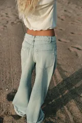 Jeans de tiro medio y corte ancho, confeccionados en denim con lavado estilo vintage de efecto desgastado. Presentan diseño de doble cinturilla superpuesta, cinco bolsillos tradicionales, trabillas para cinto y cierre frontal con cremallera y botón metálico.