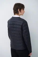 Campera acolchada tipo puffer en color beige, con diseño sin cuello y cierre frontal con botones a presión.