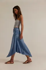Falda larga de denim, de tiro medio y línea A, con abertura frontal, paneles con costuras y ruedo deshilachado en punta.