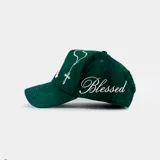 Gorra tipo baseball color verde, con bordado frontal de las letras 'LA' en tipografía gótica y una paloma blanca en el lateral. Cuenta con cierre ajustable en la parte posterior.