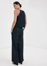 Pantalón largo wide leg de tiro medio confeccionado en tejido de algodón estilo denim, con bolsillos laterales y cierre frontal de botones, gancho y cremallera.