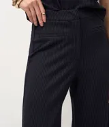 Pantalón de corte wide leg confeccionado en tejido punto roma, con diseño de raya de tiza, cintura estructurada, bolsillos delanteros y cierre frontal discreto.