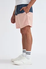 Short de baño con diseño de bloques de color, presentando una franja superior en azul marino y el resto de la prenda en color rosa. Cuenta con cintura elástica con cordón ajustable.