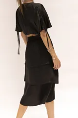 Falda midi negra de seda con cierre invisible lateral, elástico en la cintura y volados.