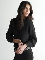 Sweater de punto negro con cuello redondo y detalle de lazo en los hombros.