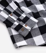 Camisa de franela a cuadros rojos y negros, de corte regular, manga larga y cuello inglés.