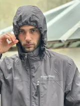 Campera impermeable azul marino con capucha ajustable y cierre frontal completo. Cuenta con bolsillos laterales y un bolsillo frontal con cierre en el pecho, además de puños elásticos.