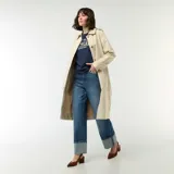 Trench midi color beige con cuello camisero, cierre frontal de botones y bolsillos laterales. Diseño clásico de gabardina con solapas y estructura fluida.