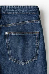 Jean de cinco bolsillos en denim de algodón, de corte estándar y piernas ajustadas, con lavado azul y efecto deslavado.