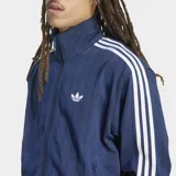 Campera deportiva Adidas Originals Firebird Drop Needle de color azul marino, con cierre frontal, cuello alto y bolsillos laterales. Presenta las clásicas tres tiras blancas en las mangas, el logotipo del Trifolio bordado en el pecho y un sutil patrón de rayas verticales en relieve.