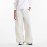 Pantalón cargo New Balance de corte amplio y tiro medio, confeccionado en tela técnica ligera de color blanco. Presenta cintura elástica con cordón ajustable, bolsillos laterales tipo cargo y diseño de pierna recta.