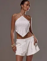 Top blanco con textura, escote halter y espalda descubierta.