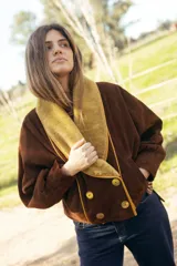 Chaqueta corta de gamuza marrón, con amplio cuello smoking y solapas de corderito en color mostaza, diseño cruzado con doble abotonadura, mangas amplias y bolsillos exteriores.